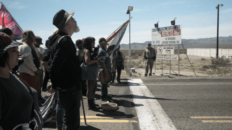 Still 2-Peace activists standing at the entry to the Nevada National Security Site_ To Use a Mountain (Credit_ To Use a Mountain, LLC )